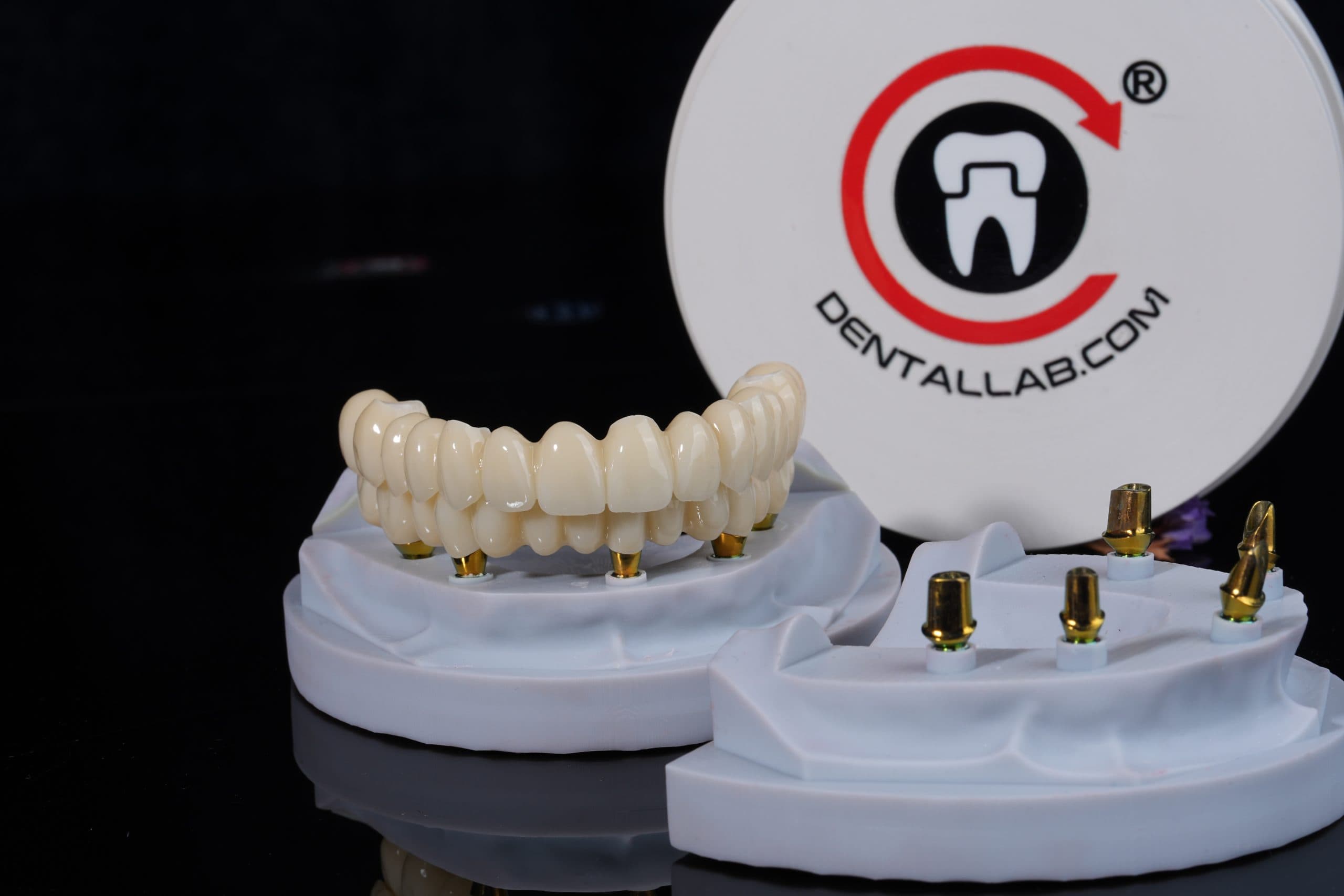 Full-arch dental restorations on implant models beside a Dentallab.com logo
